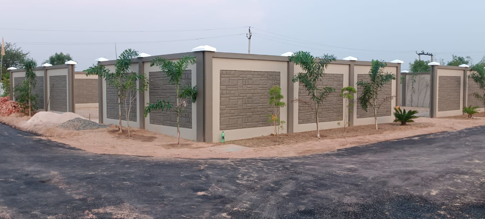 Compound wall in cream panel finish with palm trees behind